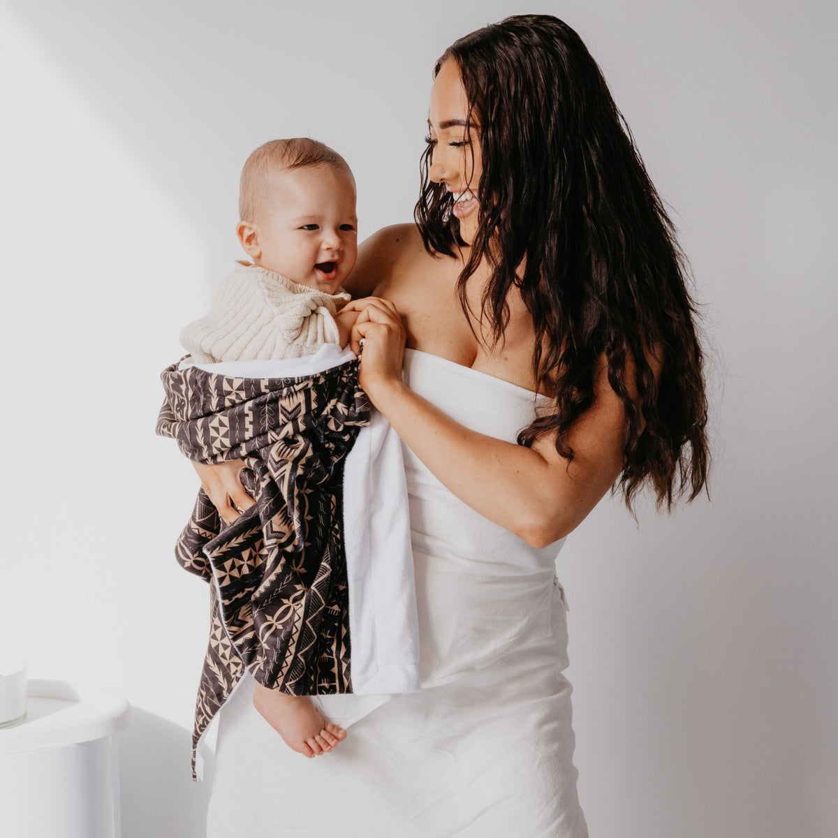 Mother holding baby with a black and beige Polynesian-inspired minky baby blanket