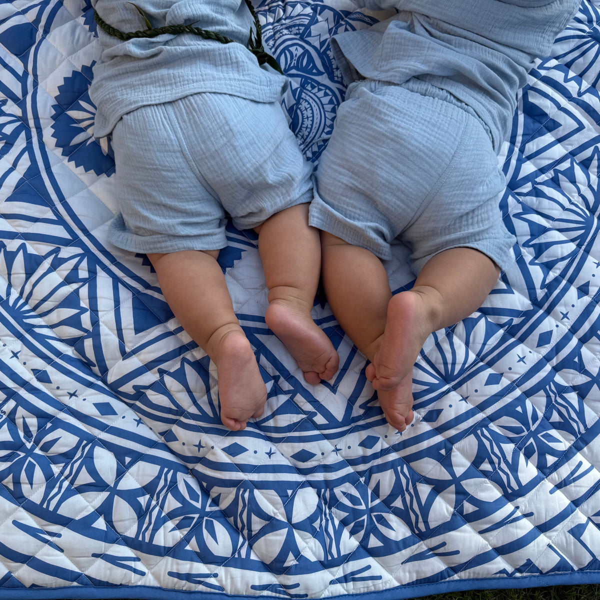Two babies lying together on a Royal Blue Pacific-inspired cotton baby playmat